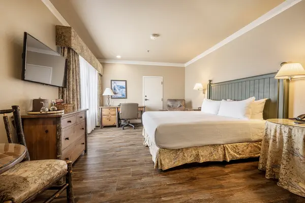 Deluxe hotel room with a king-size bed, armchairs and a wall-mounted TV