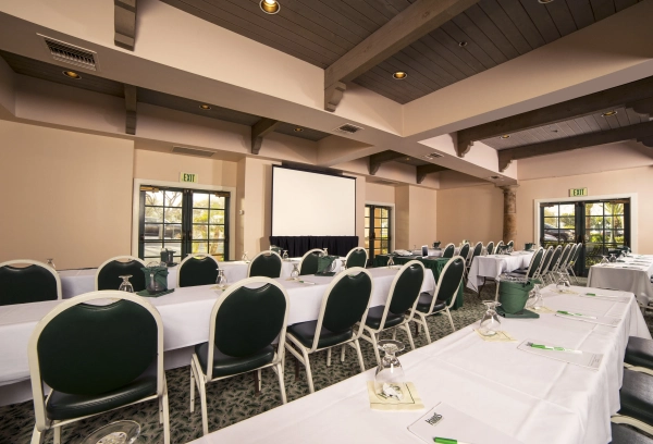Long meeting tables with green chairs and a projector screen