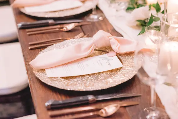 Place setting with gold charger, blush napkin and menu card