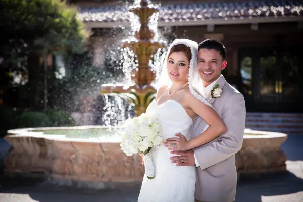 Bride and groom embracing in front of the courtyard fountain